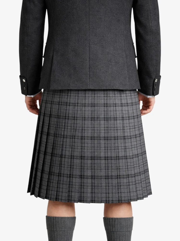 Person wearing a gray jacket with a plaid kilt on a white background