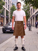 A man stands on a city sidewalk wearing a brown faux-leather kilt, a white t-shirt, white knee-high socks, and black leather shoes. The background shows a street with buildings, a parked black Mercedes, and a bicycle.