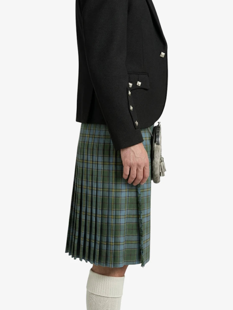 Person wearing a black jacket and green plaid kilt on a white background