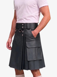 A man wearing a black faux-leather kilt with a matching belt, silver-tone hardware, and cargo pockets, paired with a light pink t-shirt against a plain white background.