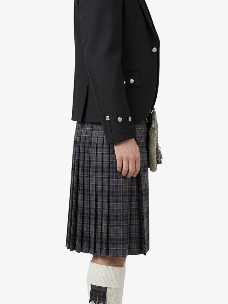 Person wearing a black jacket and plaid kilt on a white background