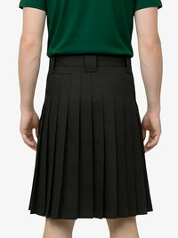 Person wearing a green shirt and black pleated skirt on a white background
