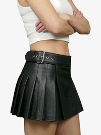 Person wearing a black pleated skirt with a white top on a plain background