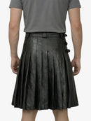 Person wearing a black pleated leather skirt on a white background
