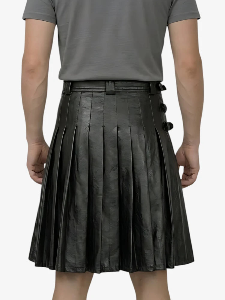 Person wearing a black pleated leather skirt on a white background