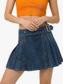 Person wearing an orange top and blue pleated skirt on a white background