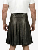 Person wearing a black pleated leather skirt on a white background