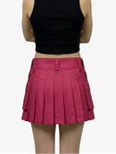 Person wearing a black crop top and pink pleated skirt on a white background
