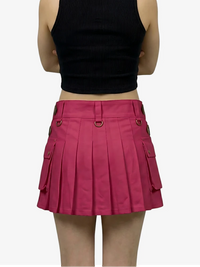 Person wearing a black crop top and pink pleated skirt on a white background