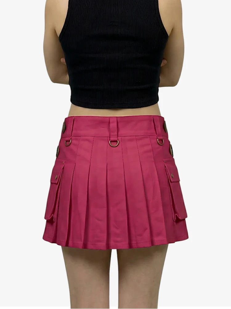 Person wearing a black crop top and pink pleated skirt on a white background