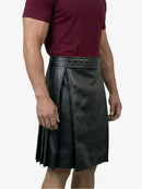 Person wearing a black leather kilt on a white background