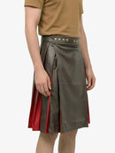 Person wearing a green leather skirt with red accents on a white background