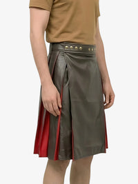 Person wearing a green leather skirt with red accents on a white background