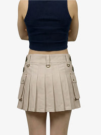 Person wearing a navy tank top and beige pleated skirt on a white background