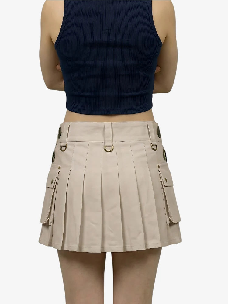 Person wearing a navy tank top and beige pleated skirt on a white background