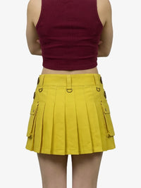 Person wearing a maroon crop top and yellow pleated skirt on a white background