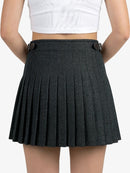 Person wearing a black pleated skirt on a plain background