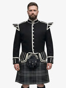 Man wearing a black doublet highland dress with white trim on a grey background