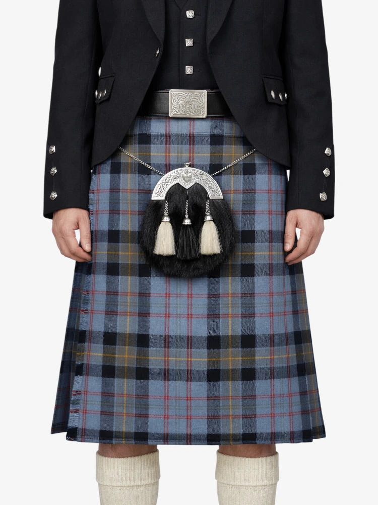 Person wearing a traditional Scottish kilt with a tartan pattern on a white background