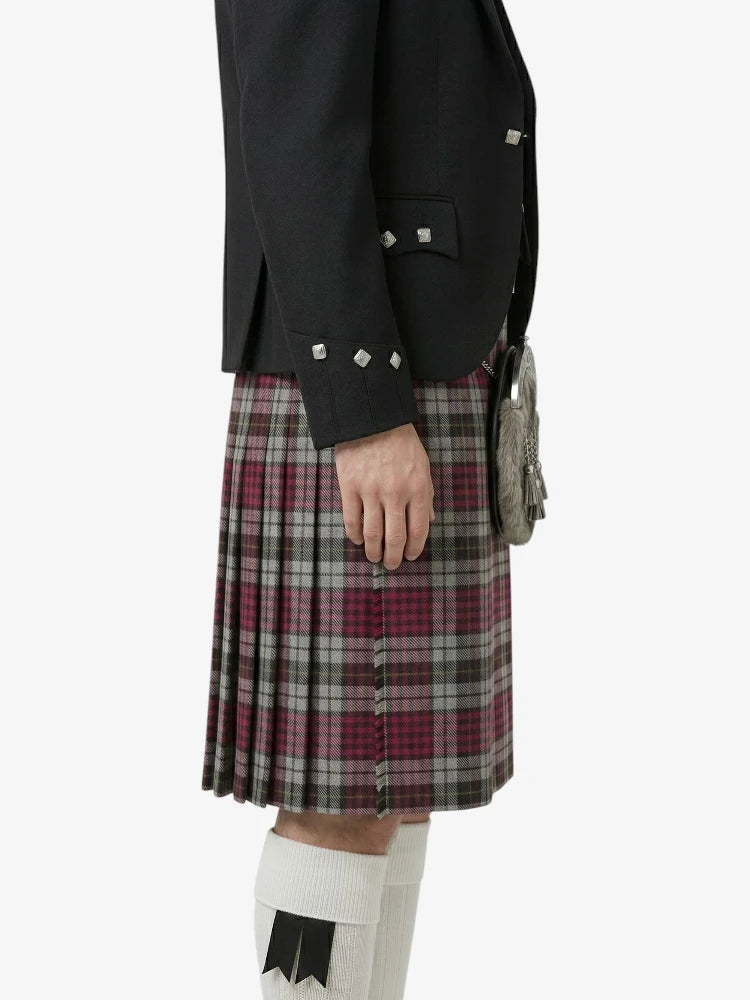 Person wearing a black jacket and plaid kilt on a white background
