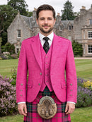 A man wearing a bright pink three-piece blazer and waistcoat with a matching pink and green tartan kilt and sporran, standing in front of a large stone mansion on a green lawn.