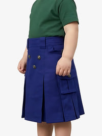 Child wearing a blue pleated skirt with a green top on a white background