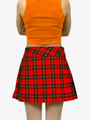 Person wearing an orange crop top and red plaid skirt on a white background