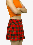 Person wearing an orange sleeveless top and red plaid skirt on a white background
