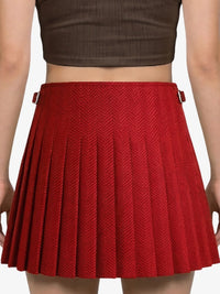 Red pleated skirt worn by a person on a plain background