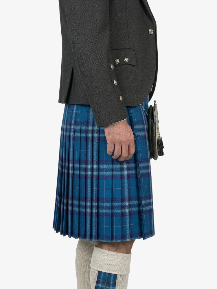 Person wearing a gray jacket and blue plaid kilt on a white background