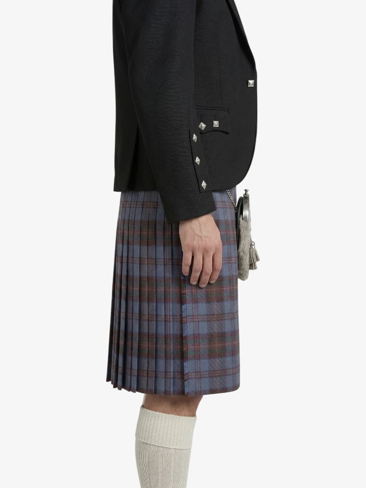 Person wearing a black blazer and plaid kilt on a white background