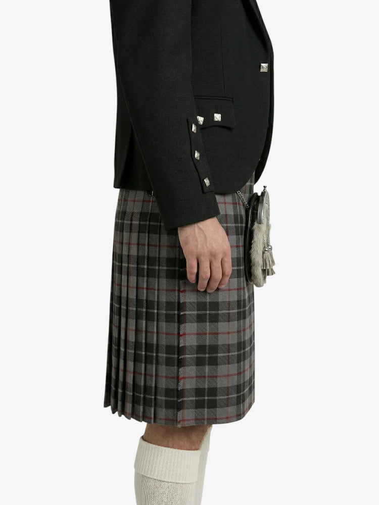 Person wearing a black blazer and plaid kilt on a white background