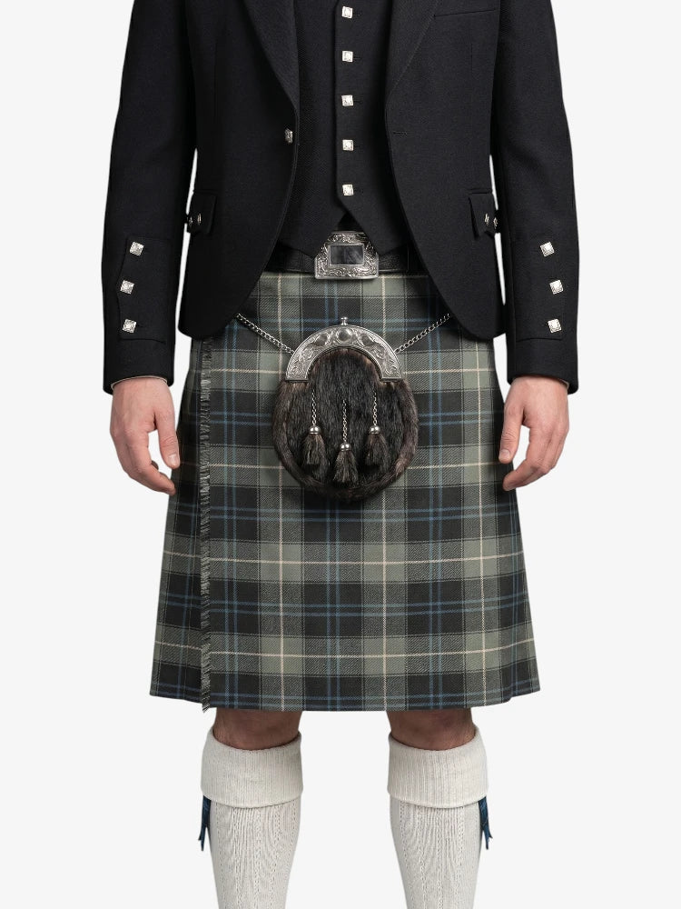 Person wearing a traditional Scottish kilt with a jacket and white socks on a white background