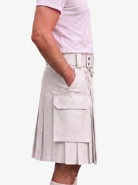 A person wearing a light beige pleated kilt with a matching belt and silver buckle, paired with a pale pink t-shirt, shown from the side against a plain white background.