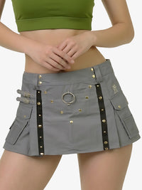 Person wearing a gray skirt with gold studs and a green top on a white background