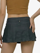 Person wearing a black pleated skirt and brown top on a white background