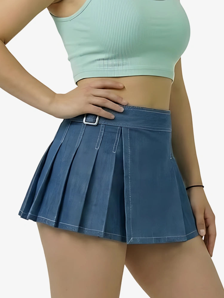 Person wearing a light green crop top and blue pleated skirt on a white background
